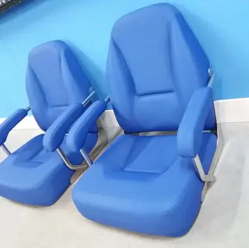 Two blue padded chairs with armrests placed against a blue wall in a room.