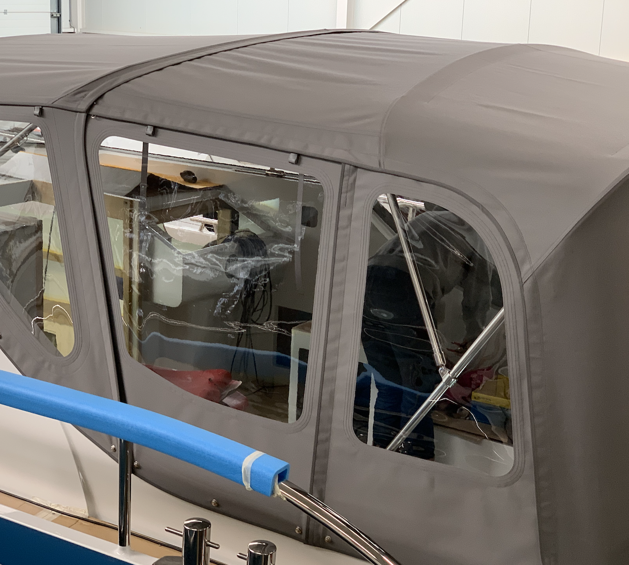 Gray aircraft cockpit canopy with window panels; a technician is visible inside, working on equipment under a fabric cover.