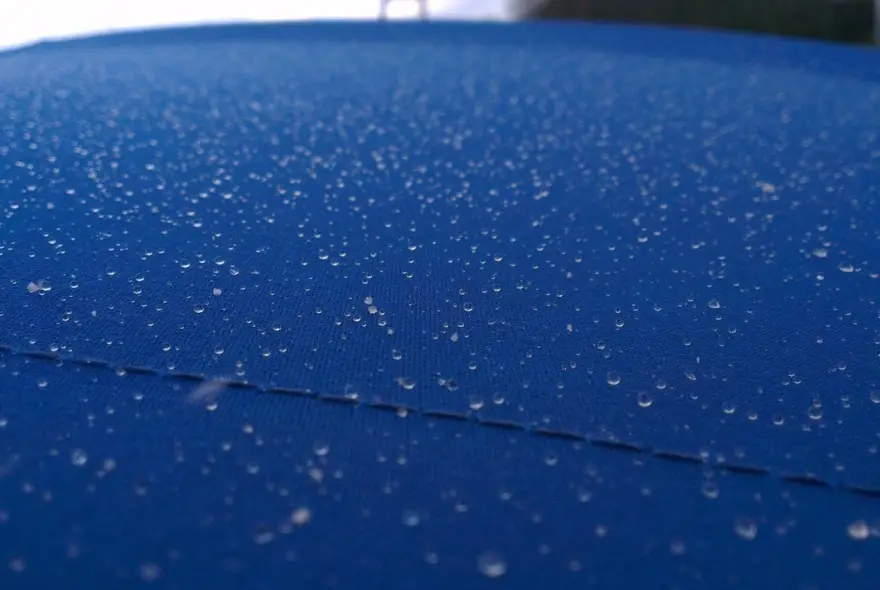 Close-up of blue fabric covered in tiny water droplets in a textured surface.