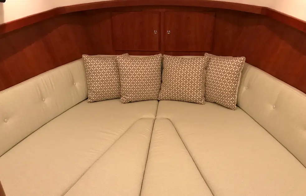 U-shaped beige sofa with four patterned throw pillows and warm wood paneling behind.