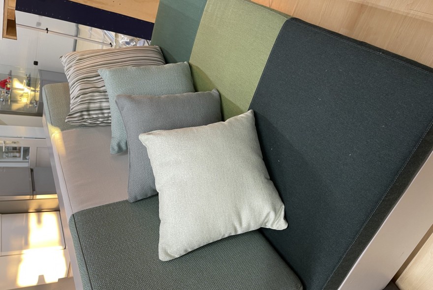 Modern fabric sofa in a showroom with multiple throw pillows in soft greens and greys